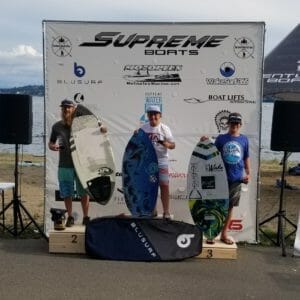 A group of people posing with surfboards at a Supreme Boats event.