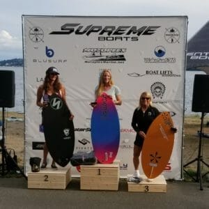 Three women on Supreme Boats podiums with surfboards.