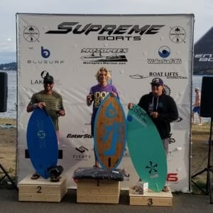 Three people standing on top of a podium with surfboards at the Supreme Boats competition.