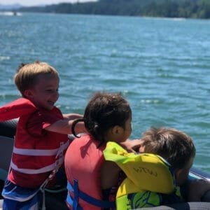 A group of kids on a Supreme boat with life jackets on.