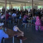 A crowd of people sitting at tables in an enclosed area at a Supreme Boats event.
