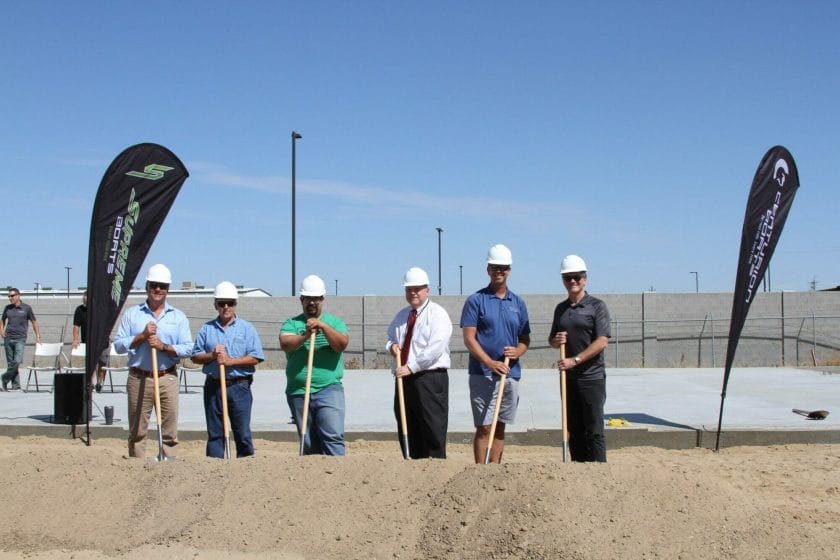 A group of men in hard hats standing next to a Supreme shovel.