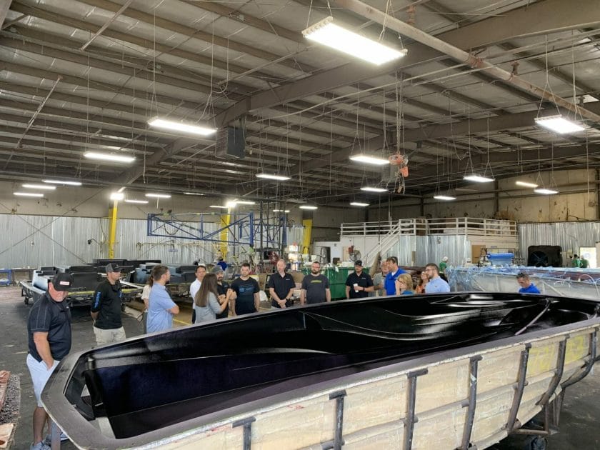 A group of people standing around a Supreme boat in a warehouse.