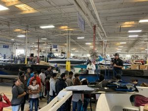 A group of people standing around a Supreme boat in a warehouse.