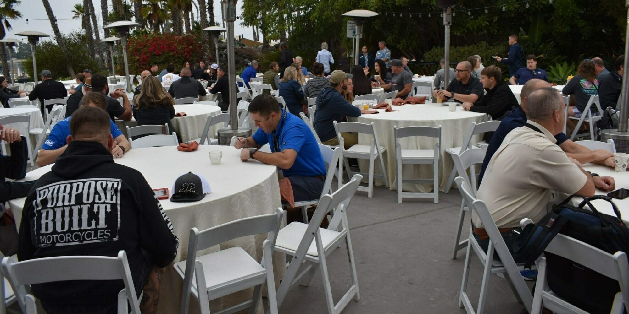 A group of people sitting at tables at an outdoor event featuring Supreme Boats.