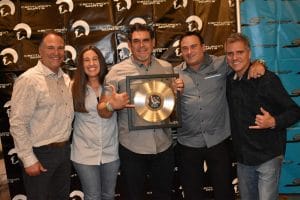 A group of people posing for a picture with a gold record from Supreme Boats.