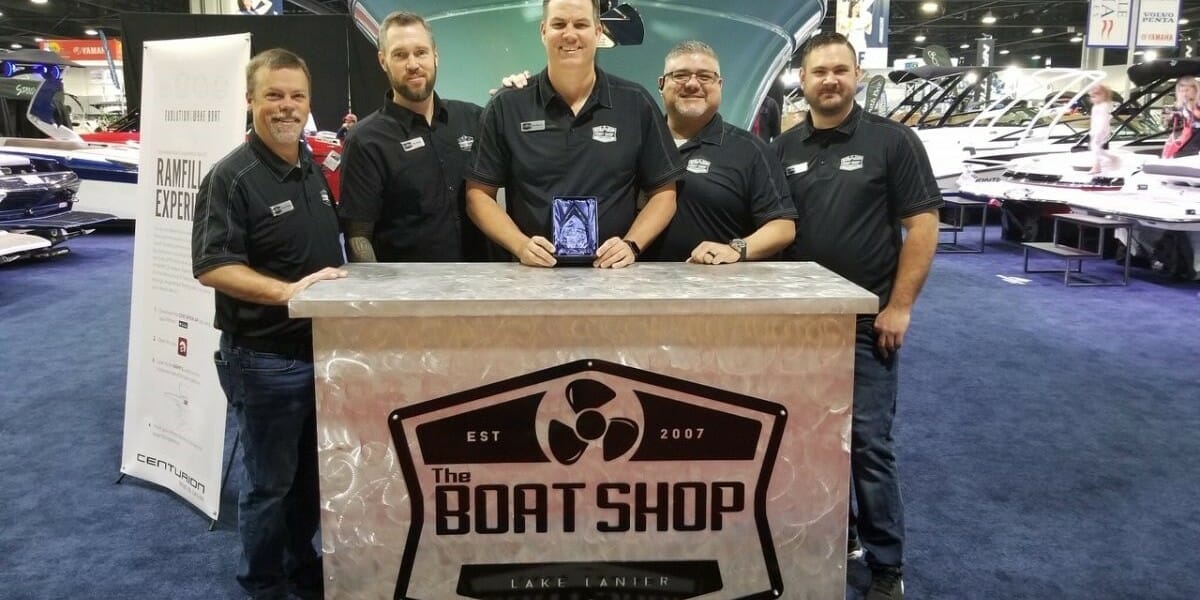 A group of men posing in front of a Supreme boat shop.