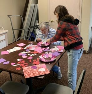Two women making supreme valentine crafts at a table.