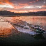 A Supreme speed boat cruising on a lake at sunset.