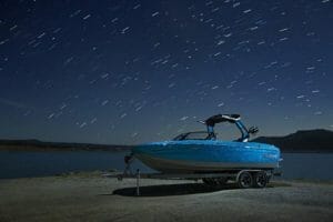 A Supreme blue boat parked next to a serene lake at night.