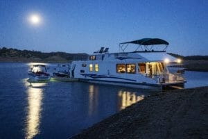 A supreme houseboat docked on a lake at night.