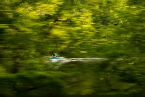 A person is riding a Supreme boat through a forest.