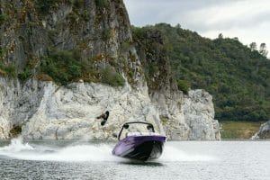 A person is riding a Supreme boat near a cliff.