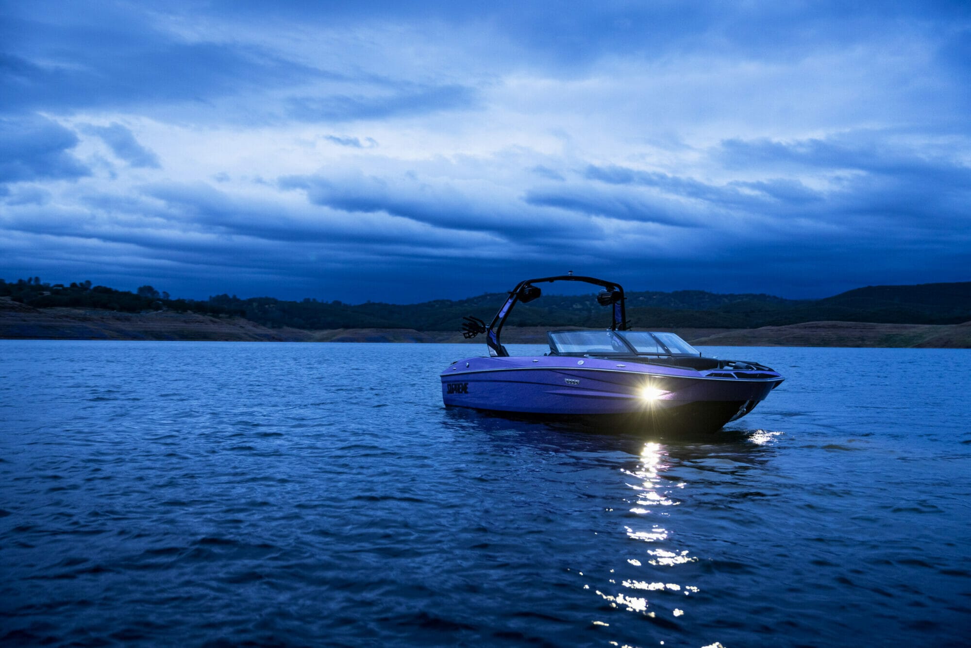 Purple S220 Supreme boat with headlights on at night