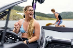 Woman smiling sitting in drivers seat of a Purple S220 Supreme boat