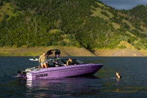 Wake surfer in water next to Purple S220 Supreme boat