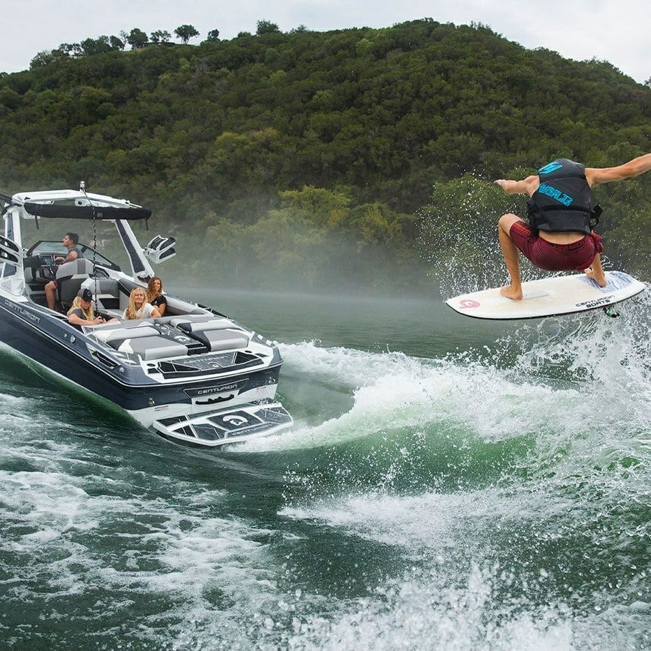 A man is wakeboarding behind a Supreme boat.