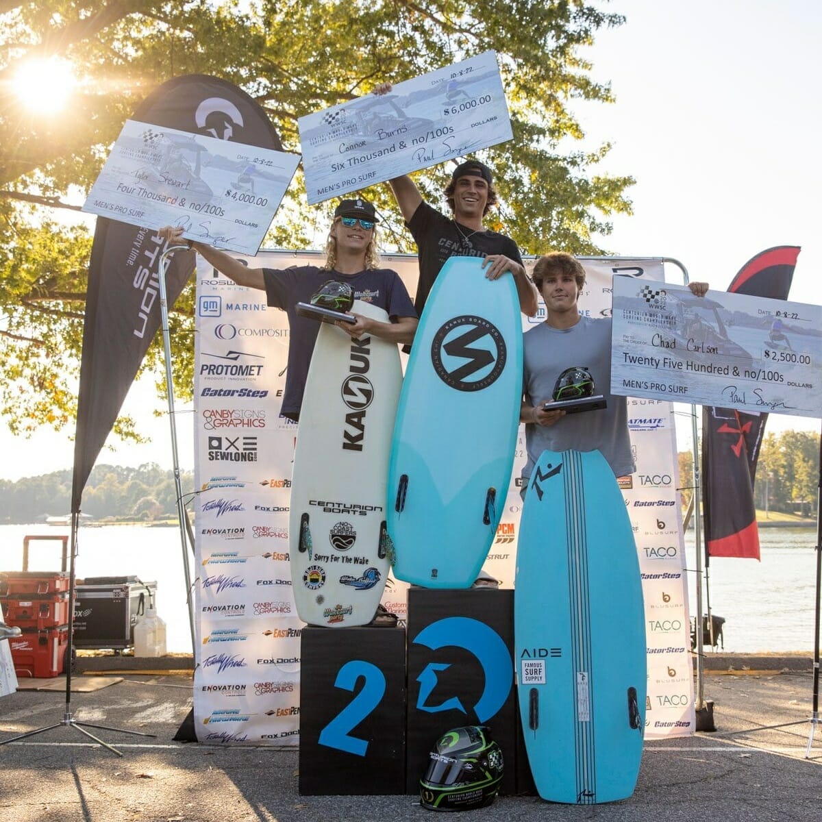 A group of people on top of a podium, holding surfboards.