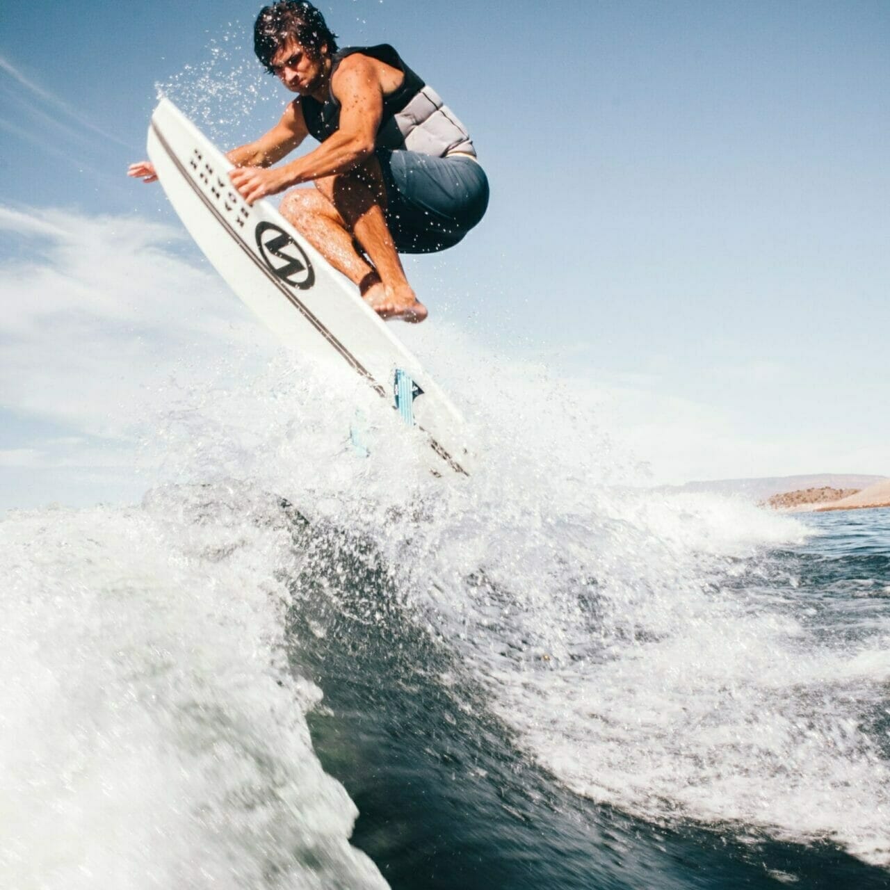 A man riding a Supreme surfboard in the air.