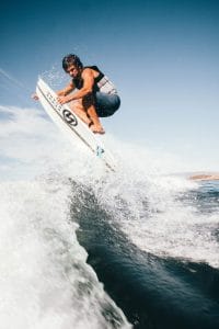 A man riding a Supreme surfboard in the air.