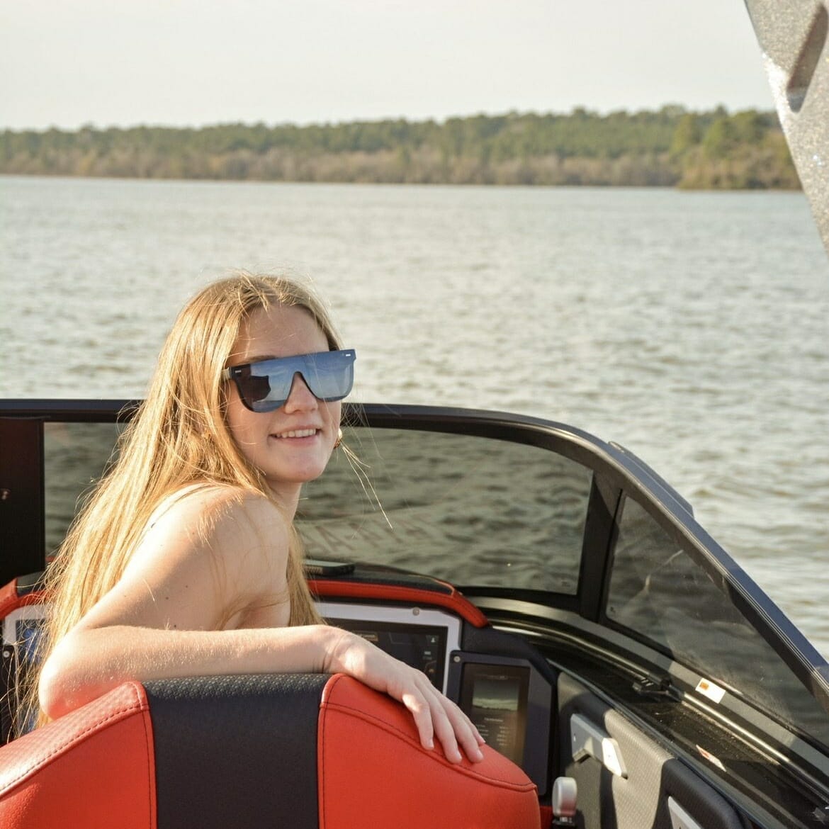 A young woman is sitting in the back seat of a Supreme boat.