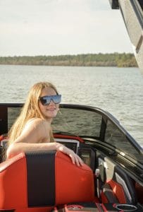 A young woman is sitting in the back seat of a Supreme boat.