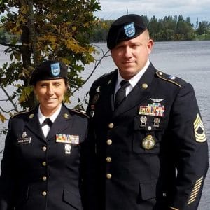 Two uniformed individuals standing next to a body of water, one man and one woman.
