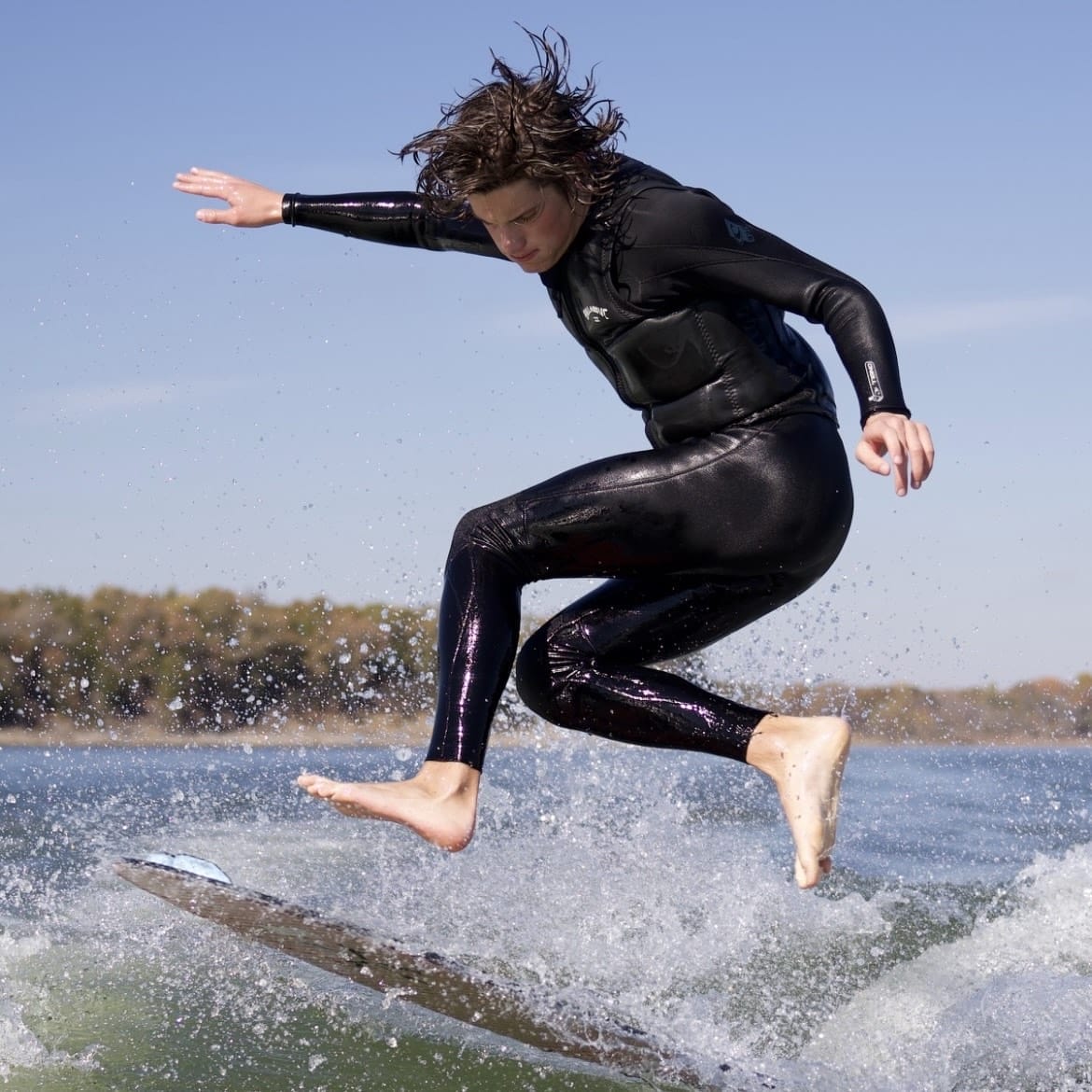 A man in a black wetsuit surfing on a surfboard.